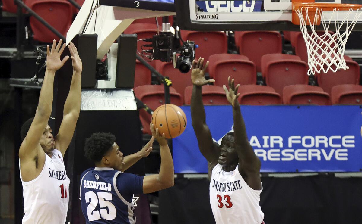 Nevada's Grant Sherfield passes as San Diego State's Matt Mitchell, left, and Aguek Arop defend March 12, 2021.