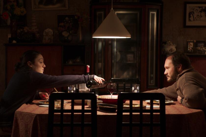 A woman pours a glass of wine for a man.