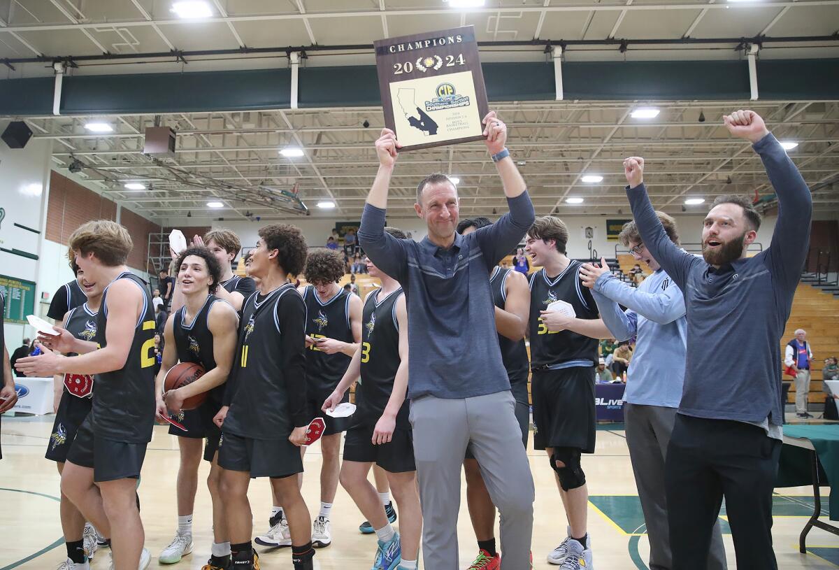 Marina head basketball coach Nick Racklin holds up the CIF Southern Section Division 2A title trophy.