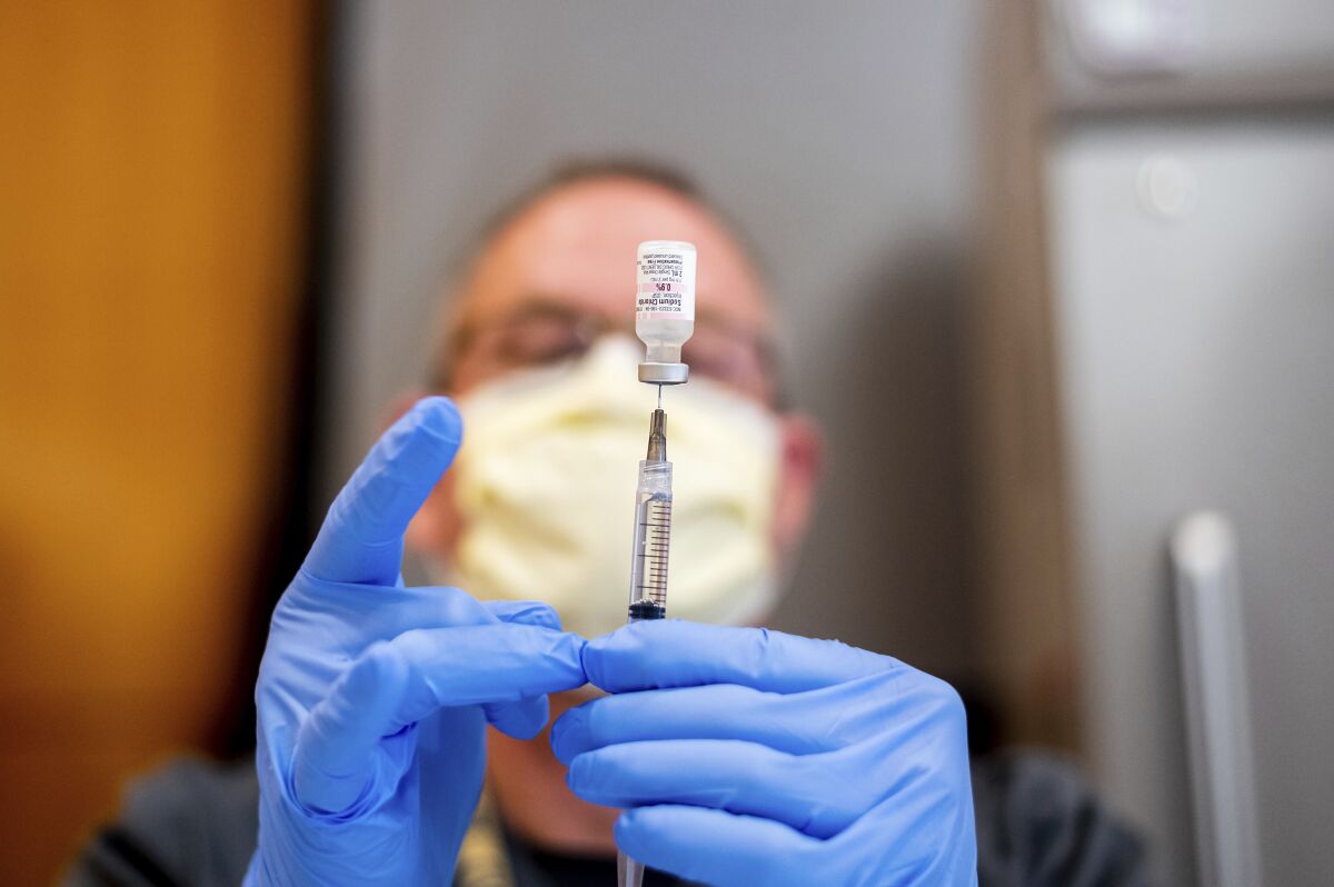 A pharmacist draws saline while preparing a dose of Pfizer's COVID-19 vaccine in Sacramento.