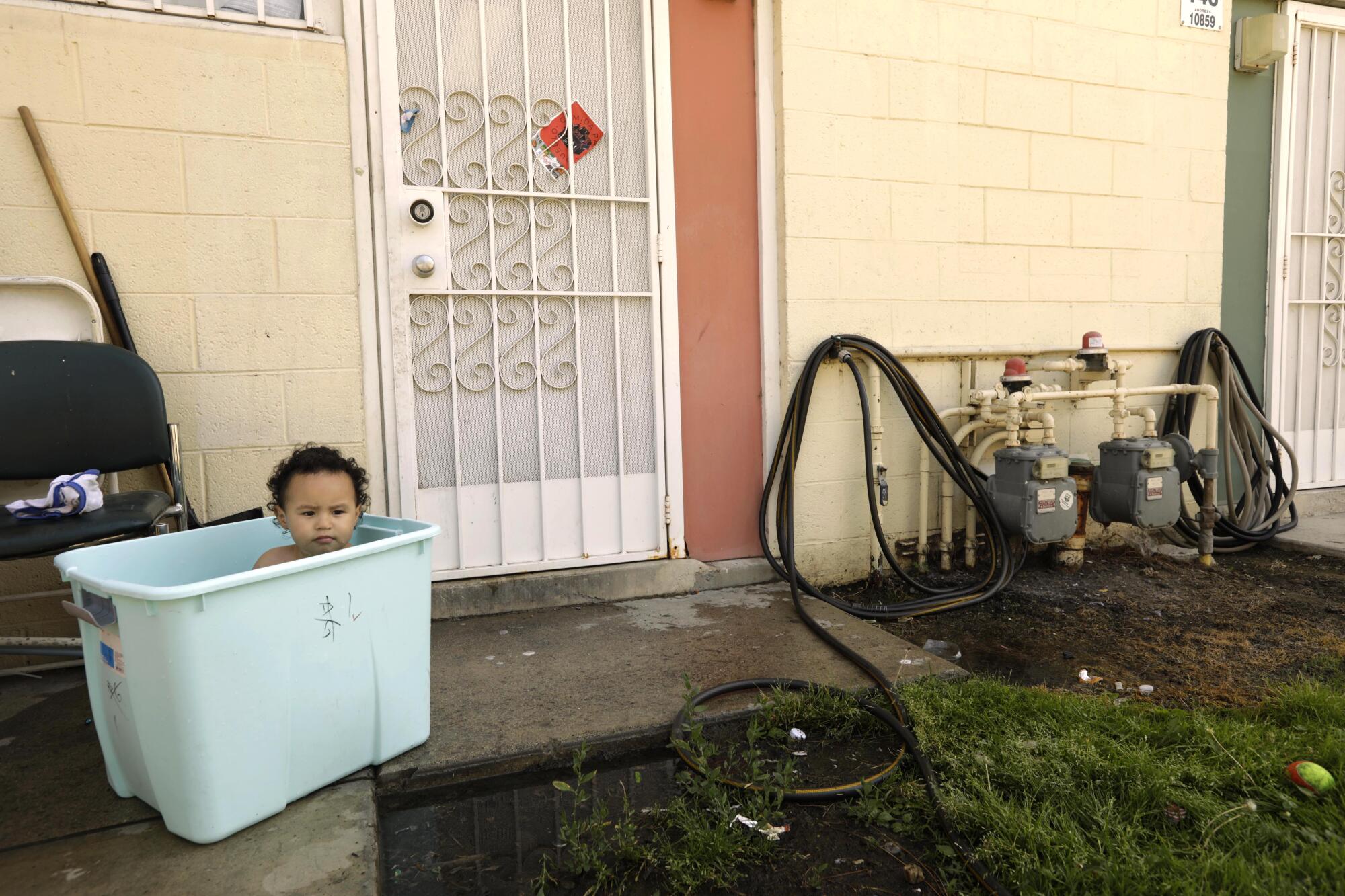 Kylian Lopez, 2, cools off in a laundry basket filled with water under the watchful eye of his mother Jocelyn Lopez.