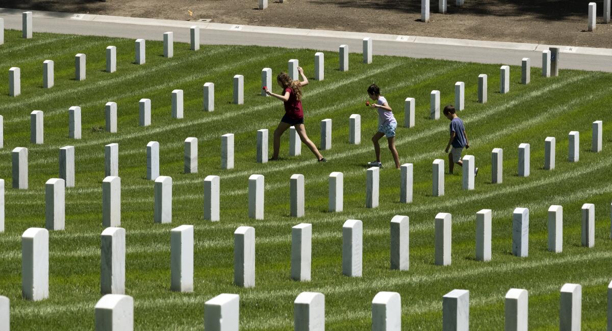 Children place flowers at the graves of fallen soldiers to pay their respects during Memorial Day observances Monday at the Los Angeles National Cemetery.