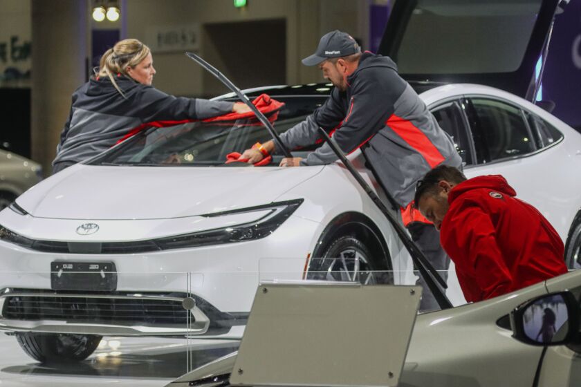SAN DIEGO, CA-Dec 29: Susan Lawrence and Rich Evans wipe down a 2023 Toyota Prius during set up for the 2023 San Diego Auto Show at the Convention Center, December 29, 2022.(Sandy Huffaker for The San Diego Union Tribune)