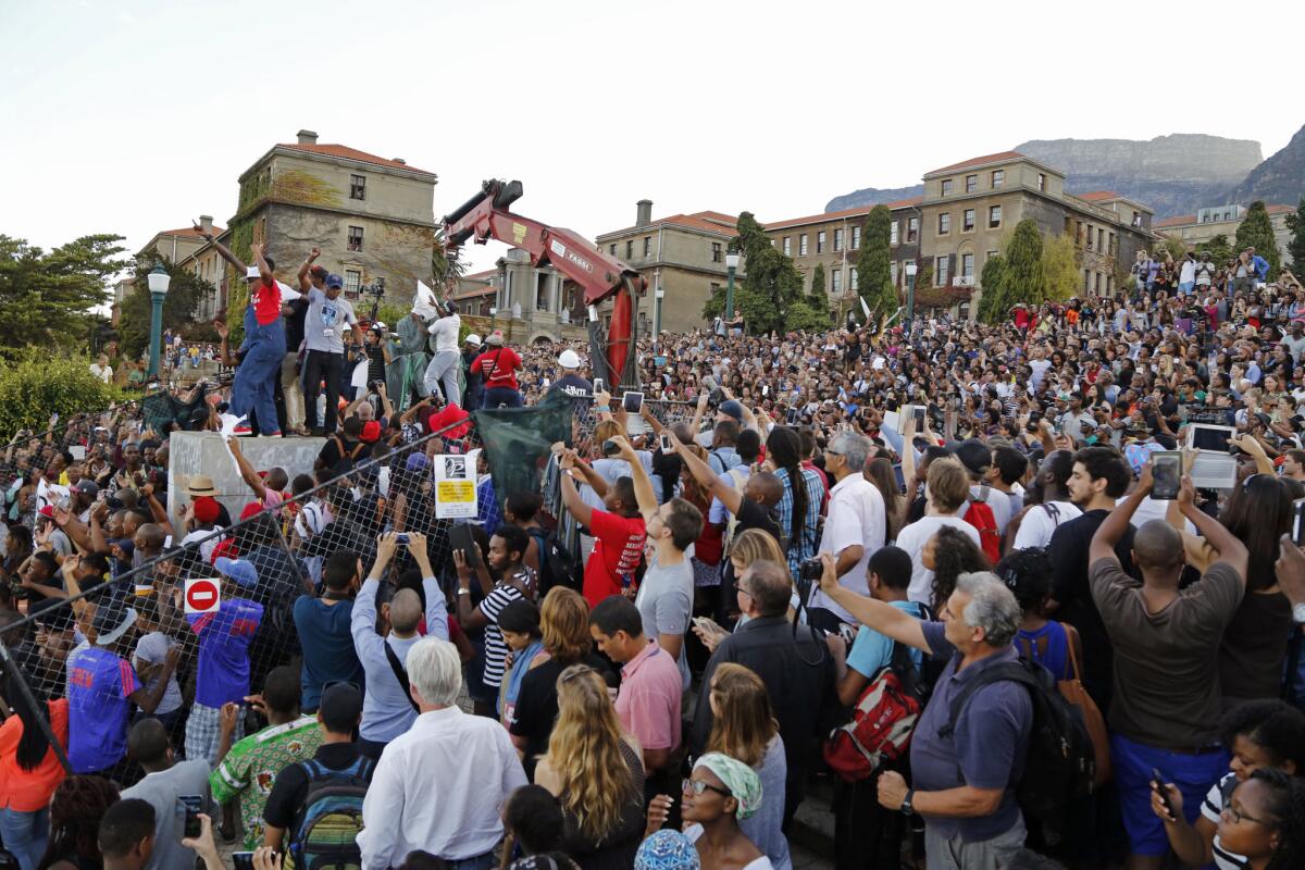 Cheering students surround the decades old bronze statue of British colonialist Cecil John Rhodes, as it is removed from the campus of Cape Town University.