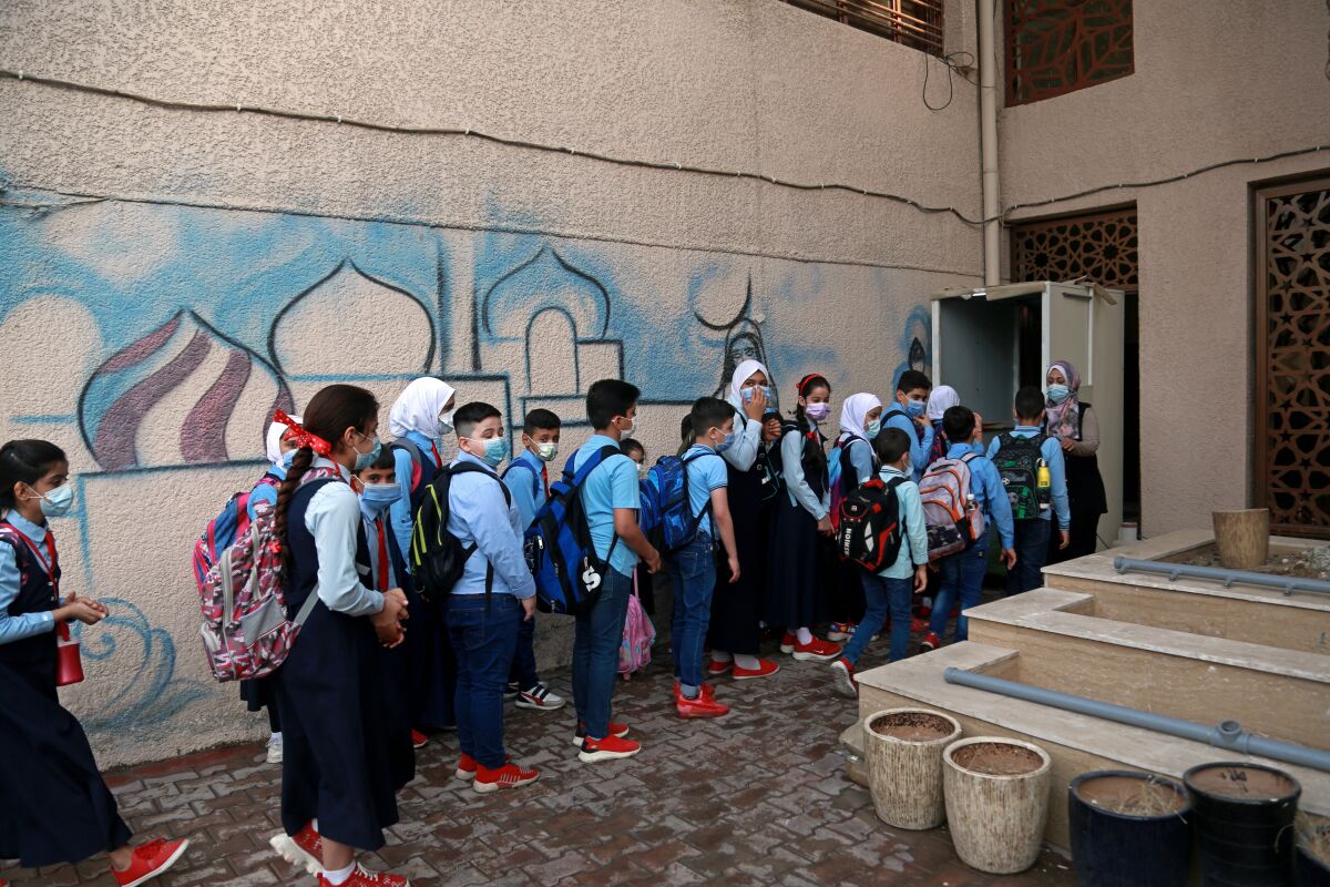 Students wearing face masks line up to enter school, in Baghdad, Iraq, Monday, Nov. 1, 2021. Across Iraq, students returned to classrooms Monday for the first time in a year and a half – a stoppage caused by the coronavirus pandemic - amid overcrowding and confusion about COVID-19 safety measures. (AP Photo/Hadi Mizban)