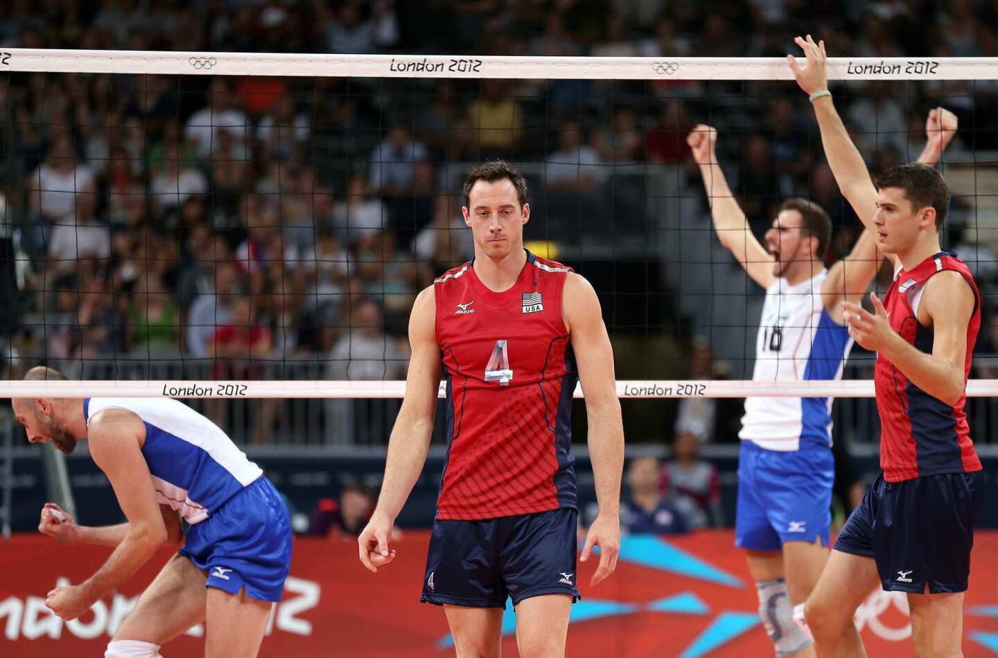 David Lee and Matthew Anderson of the United States leave court as the Russian volleyball team celebrates its victory.