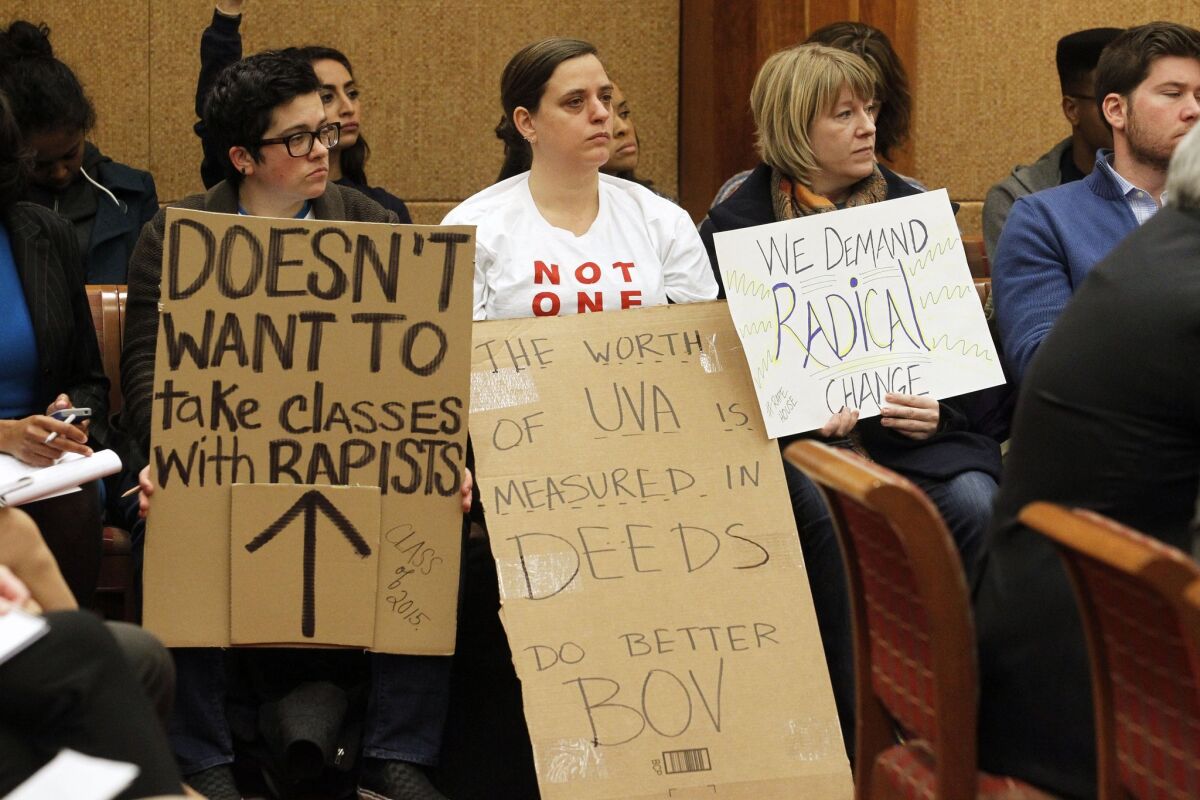 Members of the audience hold signs during a board of visitors meeting about sexual assault at the University of Virginia in Charlottsville, Va.