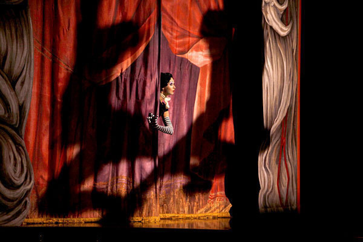 A performer peeks through the curtain in a scene from "Iris," a show about Hollywood by Cirque du Soleil. The production will end its run in January following disappointing ticket sales.
