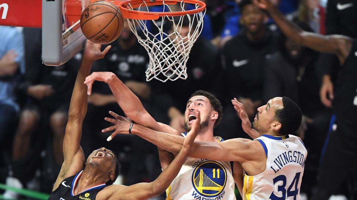 Clippers Shai Gilgeous-Alexander has his shot blocked by Klay Thompson, center, as Shaun Livingston helps on defense in the first quarter of Friday's game.
