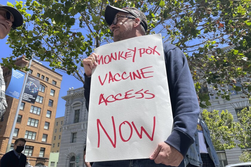 A man holds a sign that says, "Monkeypox Vaccine Access Now"