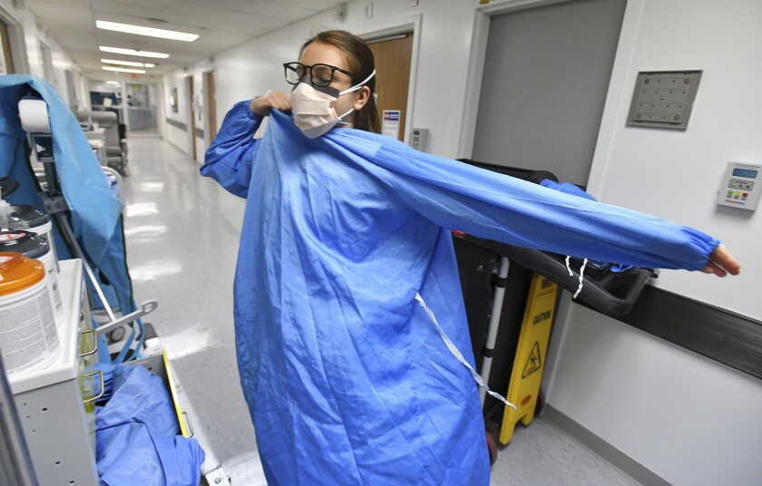 RN Zoe Zinis puts on fresh protective layers before entering the room of an infected patient in the COVID-19 ward at UF Health's downtown in Jacksonville, Fla., campus Friday, July 30, 2021. The second surge of COVID-19 infections in Jacksonville is stretching the capacity of area medical facilities to care for patients. (Bob Self/The Florida Times-Union via AP)