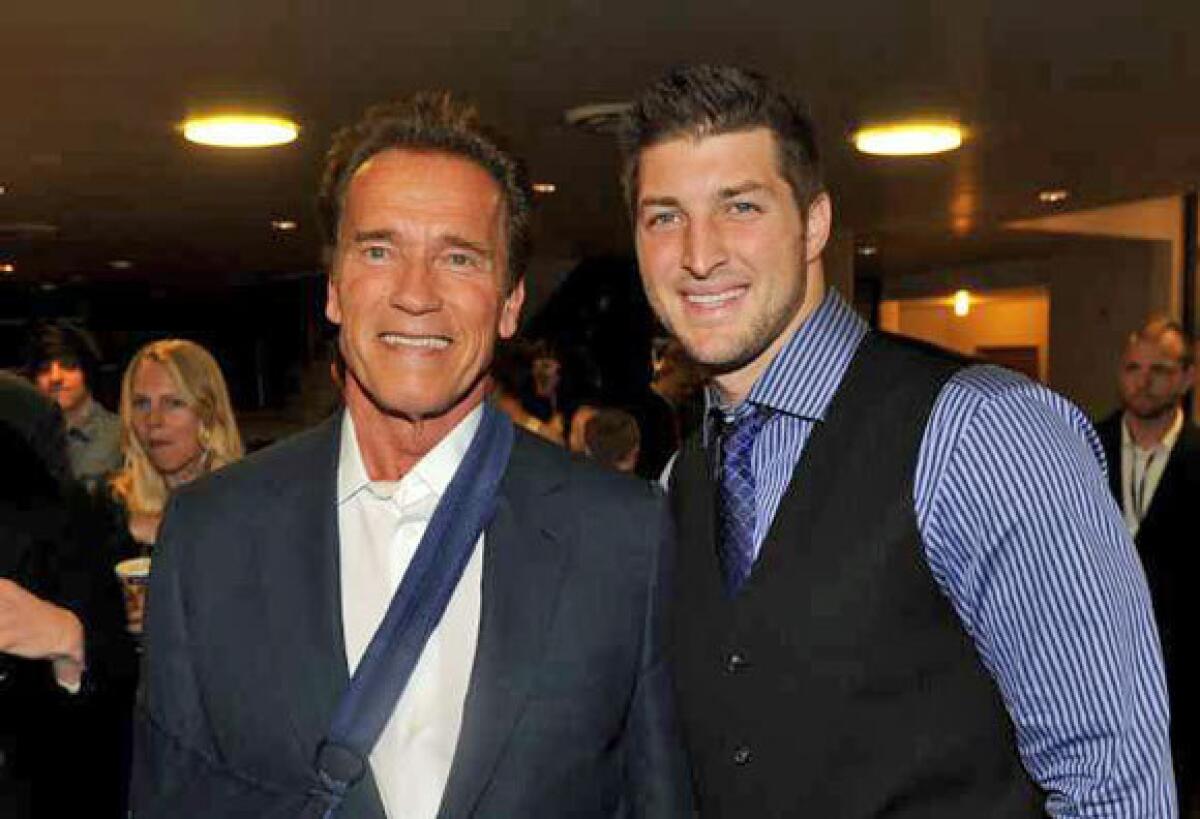 Arnold Schwarzenegger and Tim Tebow arrive at the premiere of "Act Of Valor" held at ArcLight Cinemas in Hollywood on Monday.