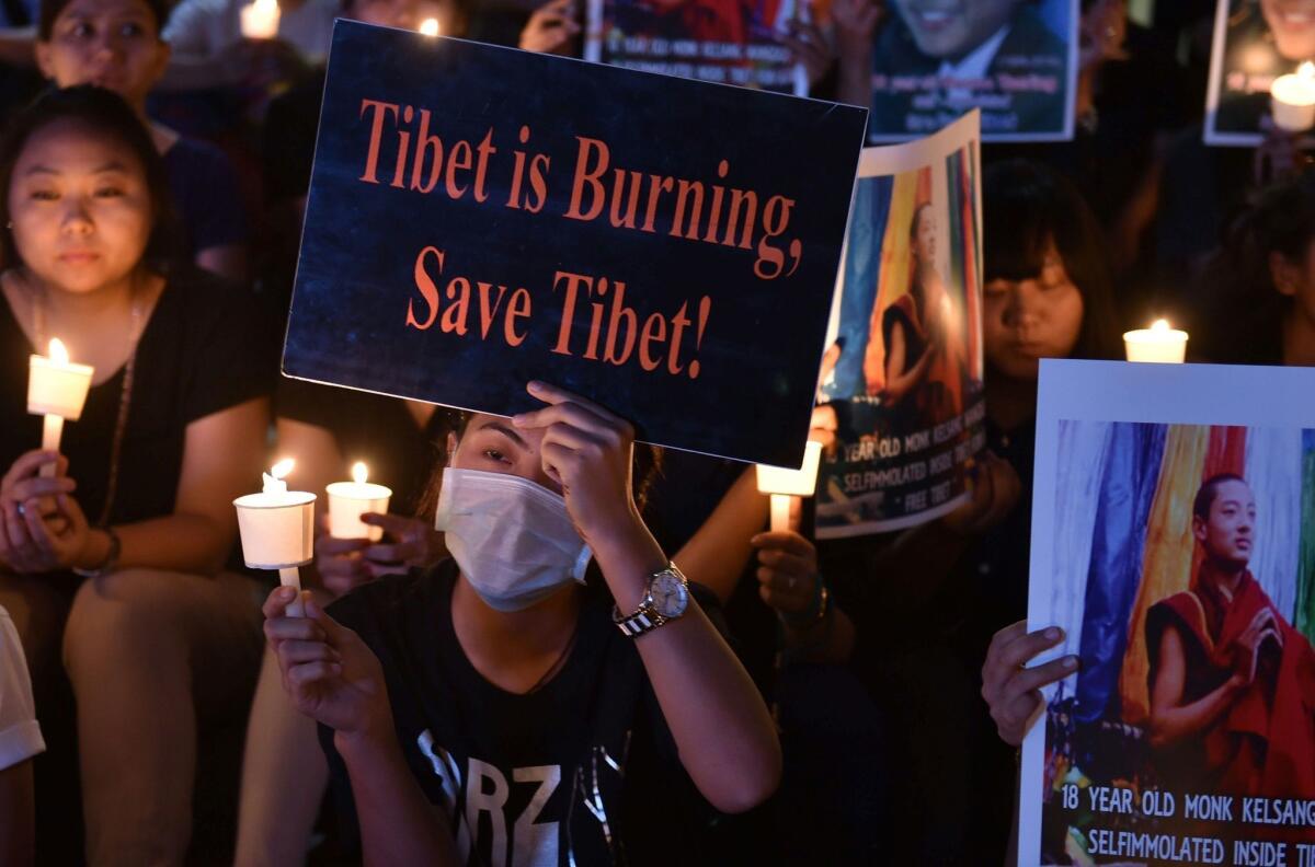 Tibetan refugees hold placards and candles during a vigil following the self-immolation of two Tibetans in Bangalore, India, on March 5, 2016.