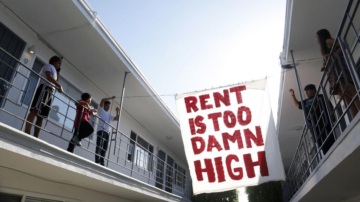 Organizers with Housing Long Beach, a local advocacy group pushing for rent control and eviction protections, hangs up a sign in the courtyard of the apartment complex on Cedar Ave. in mid-June.