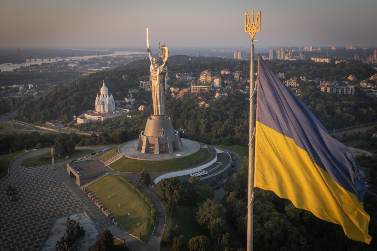 Ukrainian national flag with large monument in background