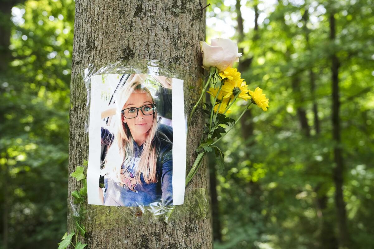 A photo of a woman is taped to a tree trunk along with flowers
