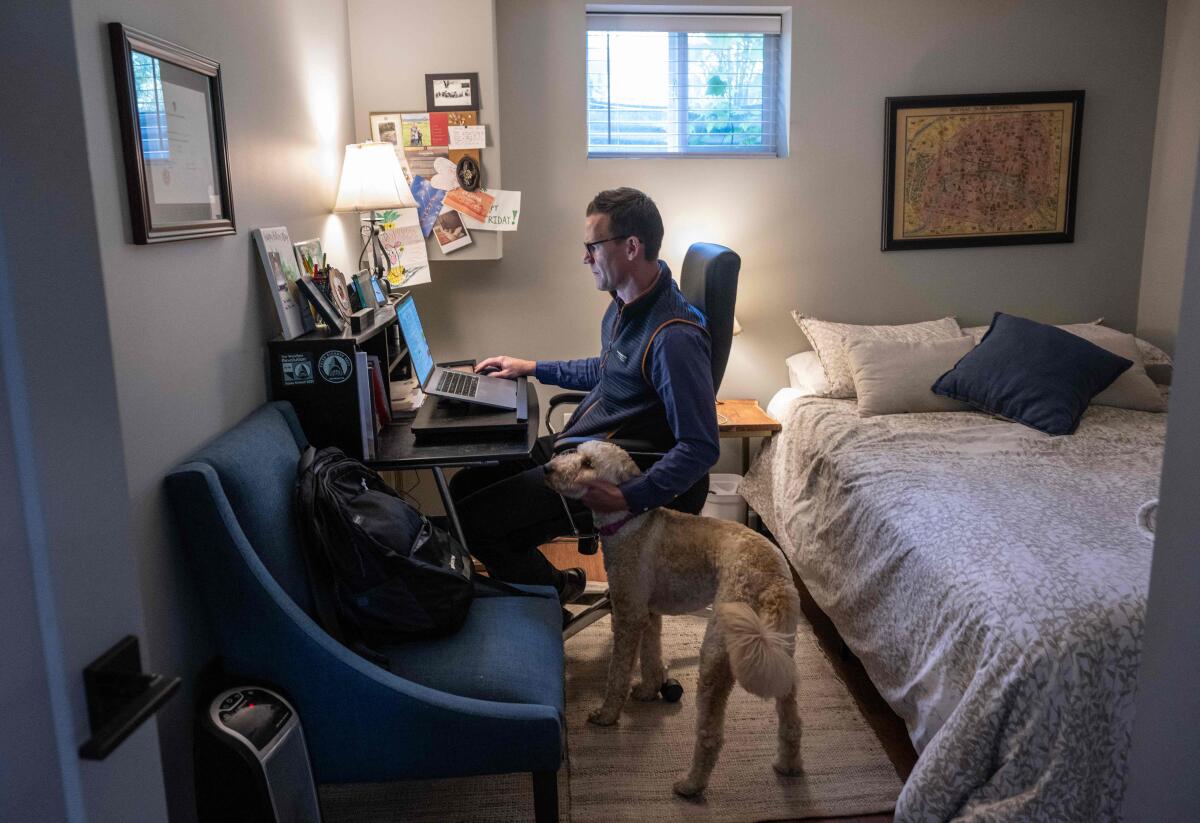 Danny Crouch pets his dog as he sits in his basement working from home in Arlington, Virginia, on May 25, 2023. 