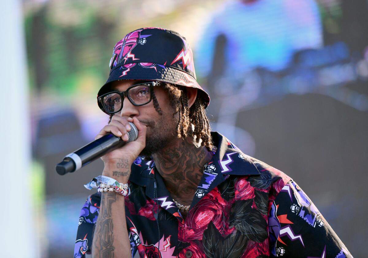 A rapper in a flowered bucket hat and matching shirt performs onstage