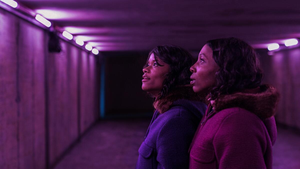 Two young women bathed in purple light in the movie "The Silent Twins."