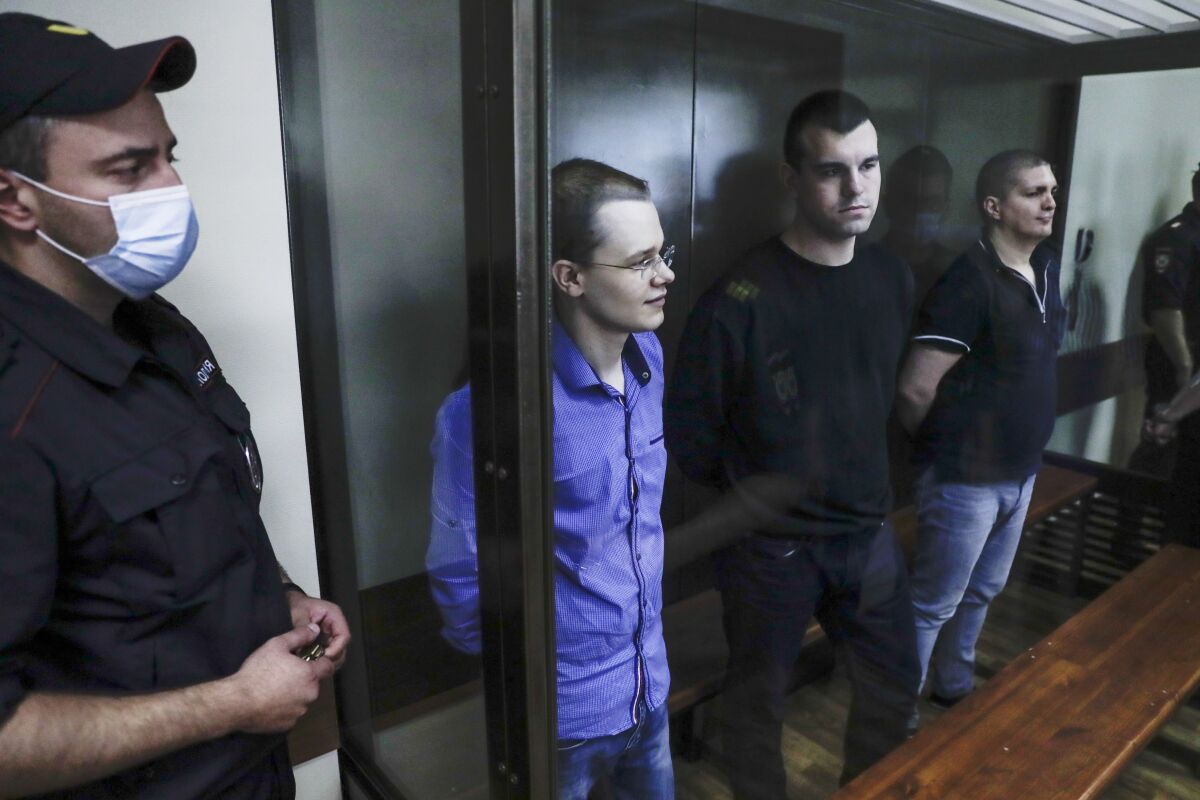 Members of the New Greatness group, who are charged with the organization of an extremist association, stand behind a glass in a courtroom prior a hearing in Moscow, Russia, Thursday, Aug. 6, 2020. Arrests of the two youngest members of the New Greatness group - 17-year-old Anna Pavlikova and 19-year-old Maria Dubovik - prompted a mass protest in August 2018, after which the two teenagers were released under house arrest. (AP Photo/Pavel Golovkin)