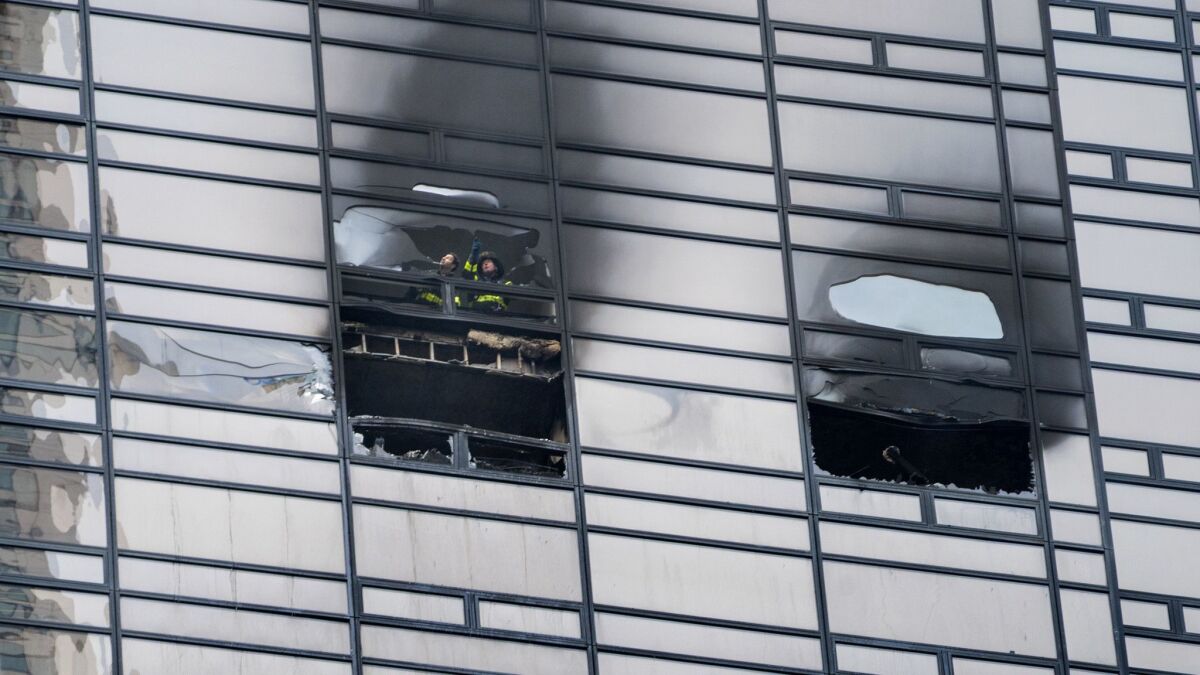 Firefighters look out from the window of a damaged apartment in Trump Tower on Saturday,