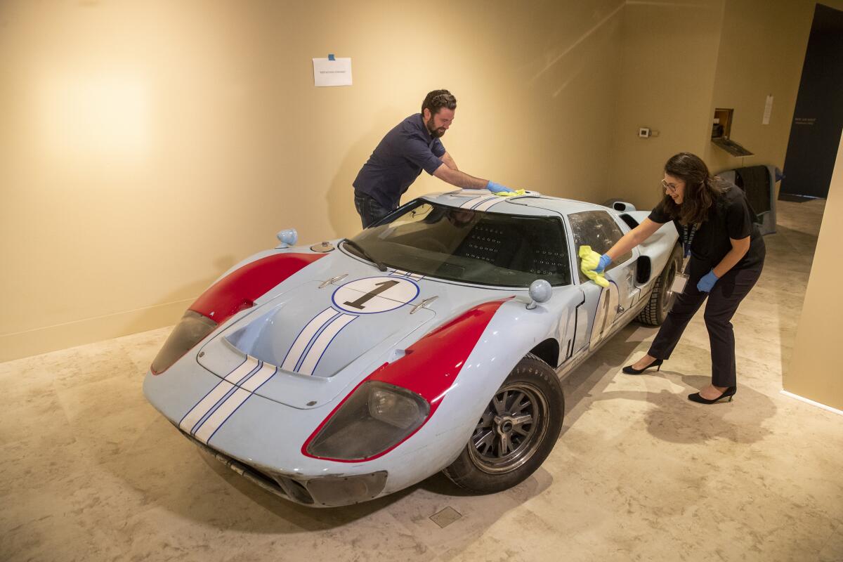 The Bowers' Victoria Gerard and Robert Maxhimer of the Walt Disney Archives wipe down the windows of the production vehicle used in the movie "Ford v Ferrari."