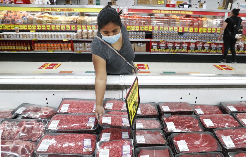 FILE - In this April 29, 2020 file photo, amid concerns of the spread of COVID-19, a shopper wears a mask as she looks over meat products at a grocery store in Dallas. U.S. wholesale prices rose 0.3% in December led by a the biggest jump in energy costs since June. The Labor Department reported Friday, Jan. 15, 2021 that the gain in its producer price index, which measures inflation pressures before they reach consumers, followed a modest 0.1% gain in November and matched the 0.3% rise in October.(AP Photo/LM Otero, File)