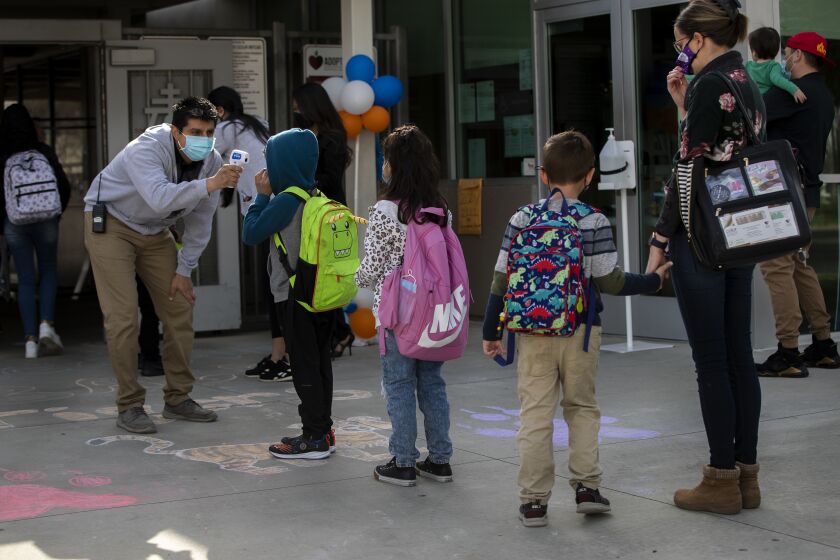 RIVERSIDE, CA - MARCH 9, 2021: Kindergarteners get their temperatures checked on the first day back to school at Pachappa Elementary on March 9, 2021 in Riverside, California. The K-6 school was closed on March 13, 2020 because of the coronavirus pandemic.The students have been divided into two groups. One group attends in-person learning on Tuesdays and the other on Thursdays. All students will stay in remote learning the other days of the week.(Gina Ferazzi / Los Angeles Times)