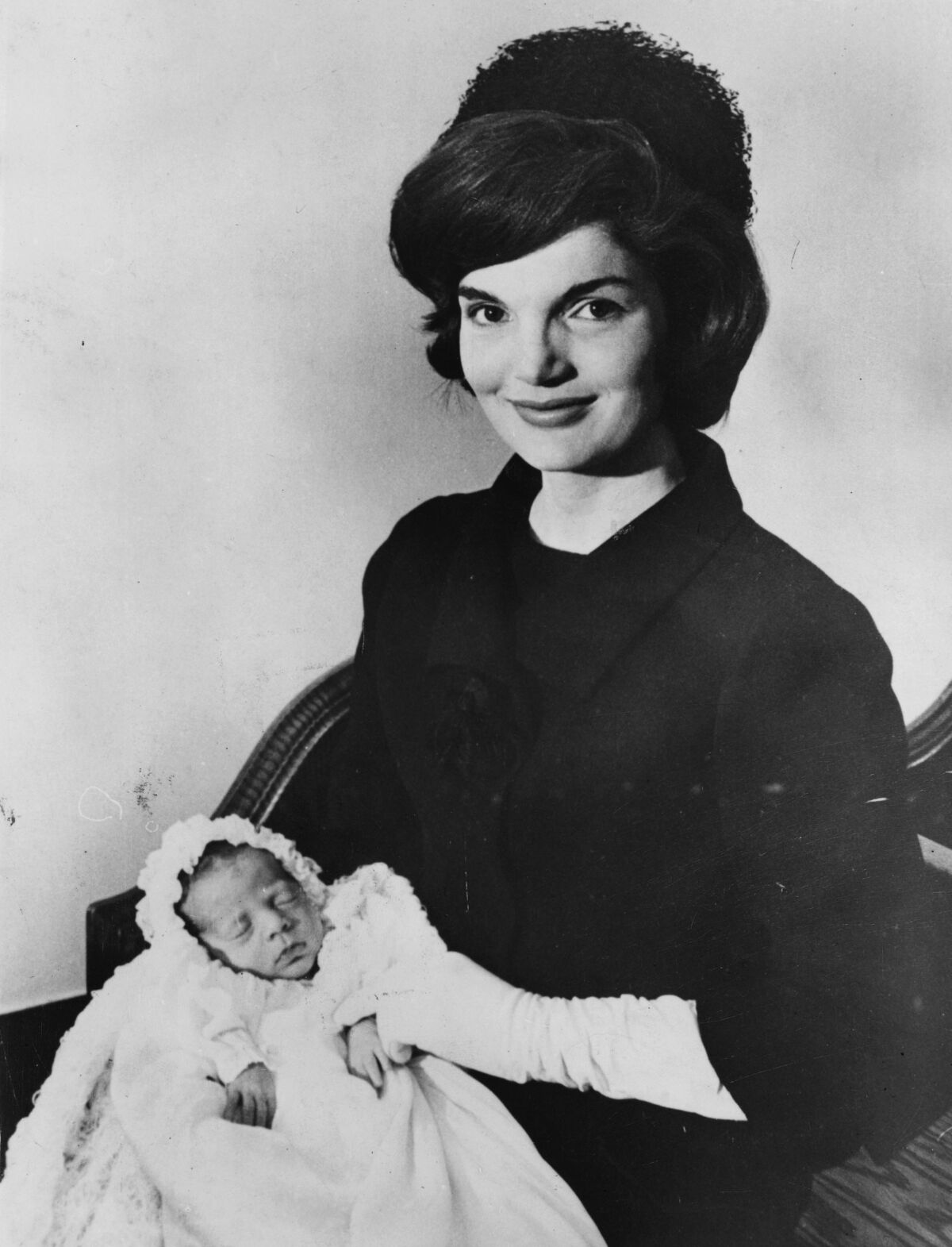 Jackie Kennedy smiles while holding a baby