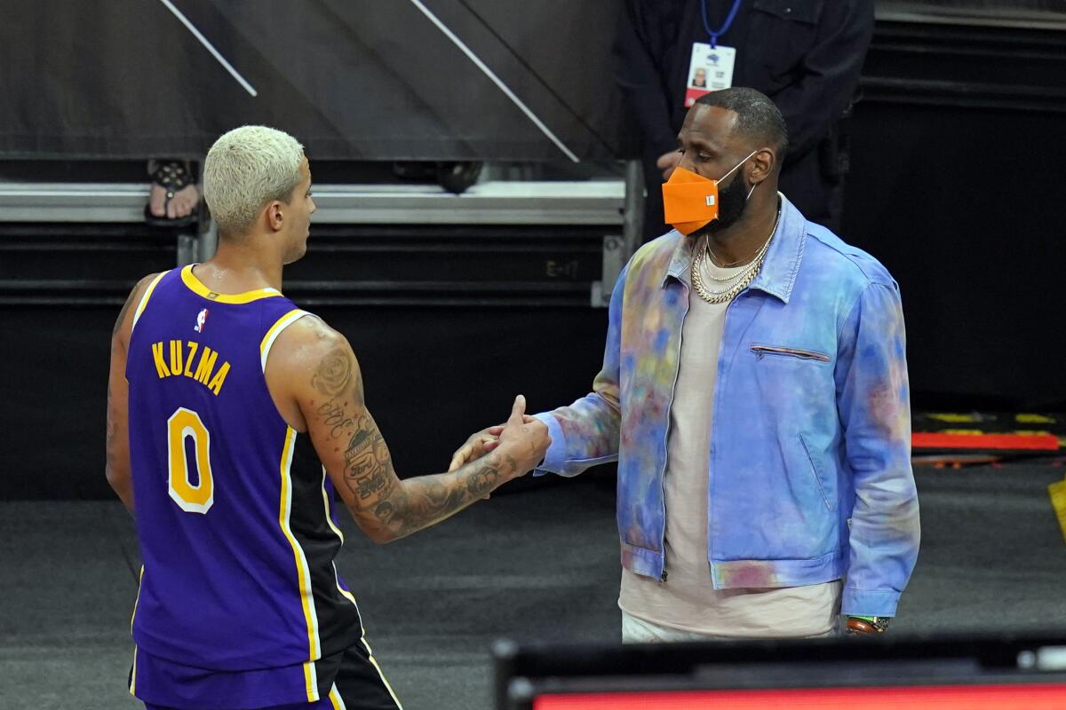 Sidelined Lakers forward LeBron James, right, greets teammate forward Kyle Kuzma.