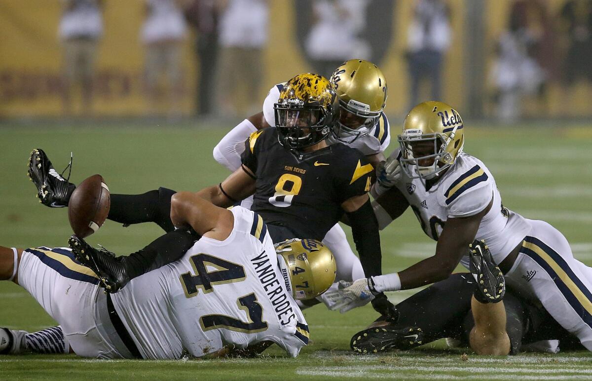Arizona State running back D.J. Foster fumbles when brought down by UCLA defenders in the first quarter.