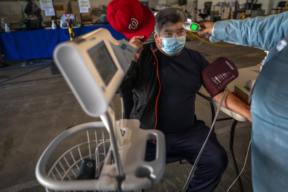 A man has his temperature checked before getting his COVID-19 vaccination