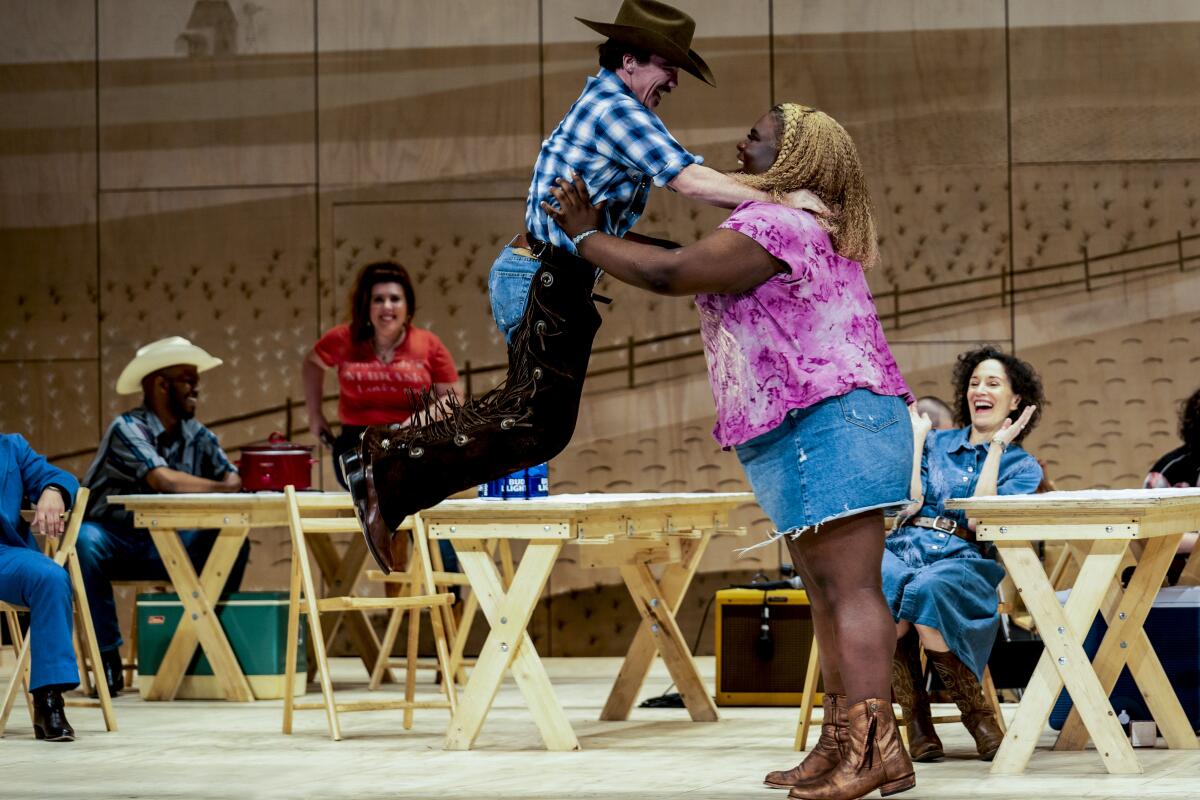 A woman picks up a man in a cowboy hat while dancing.