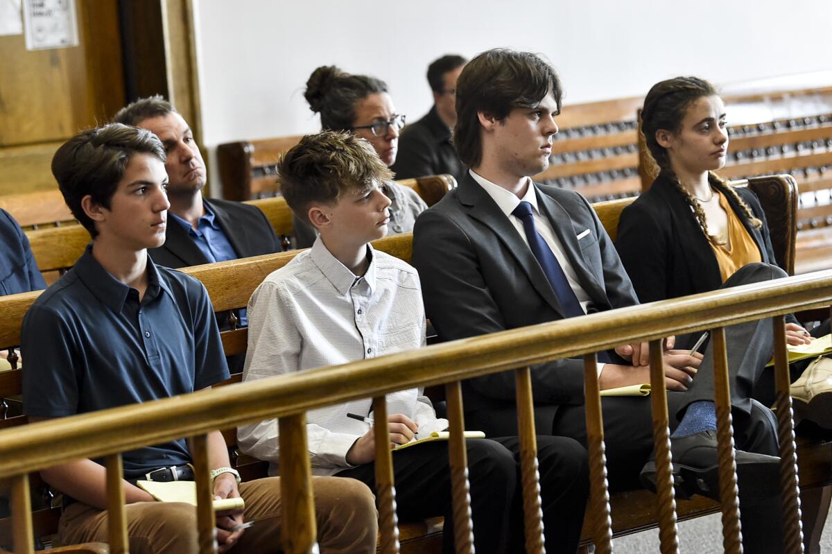 Teens and young adults sit and listen in court.