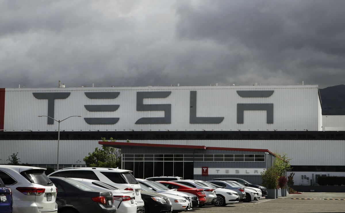 FILE - Vehicles are parked outside the Tesla plant, in Fremont, Calif., on May 12, 2020. California sued Tesla Inc. on Wednesday, Feb. 9, 2022, over allegations of discrimination and harassment of Black employees at its San Francisco Bay area factory. (AP Photo/Ben Margot, File)
