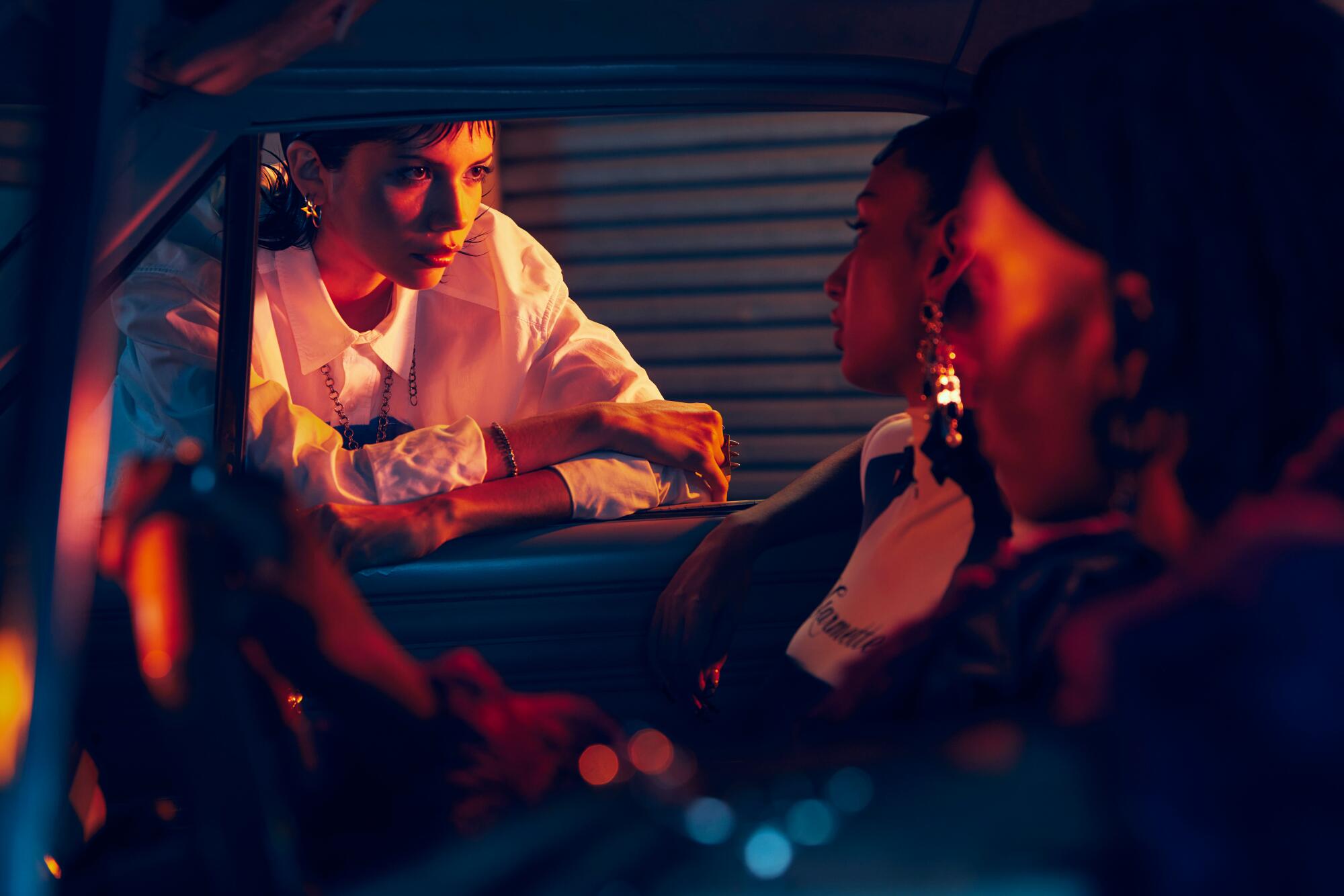 A person in a white shirt leans on the windowsill of a car.