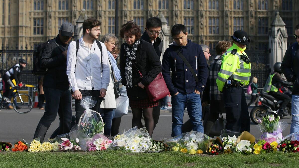 People view floral tributes to victims of Wednesday's attack outside the Houses of Parliament in London, on March 24, 2017. (Tim Ireland / AP)