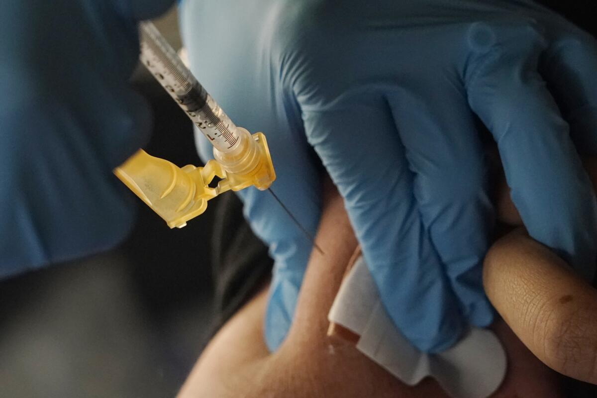 A nurse with gloved hands administers a vaccine.