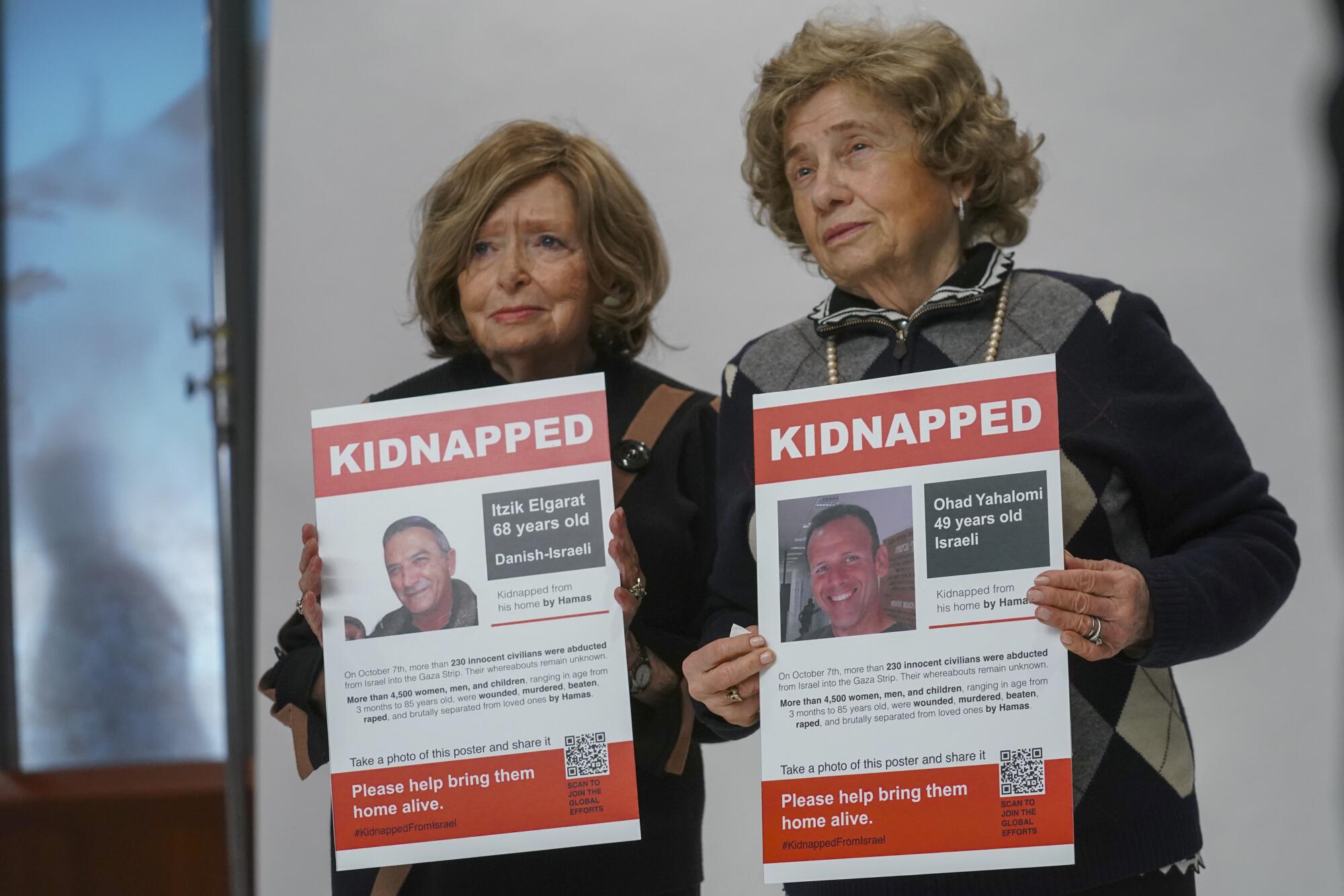 Two women hold up "Kidnapped" posters showing Israeli hostages.