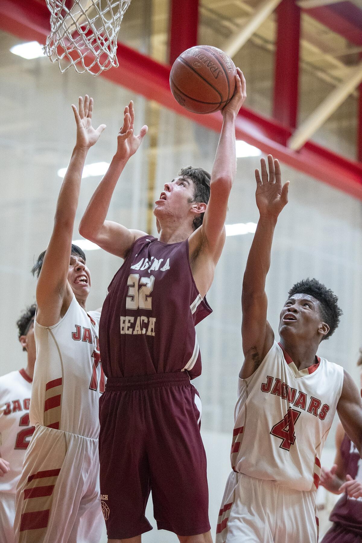 Laguna Beach's Nolan Naess goes up for a shot against Segerstrom's Alex Chavez, left, and Charles Erving, right.