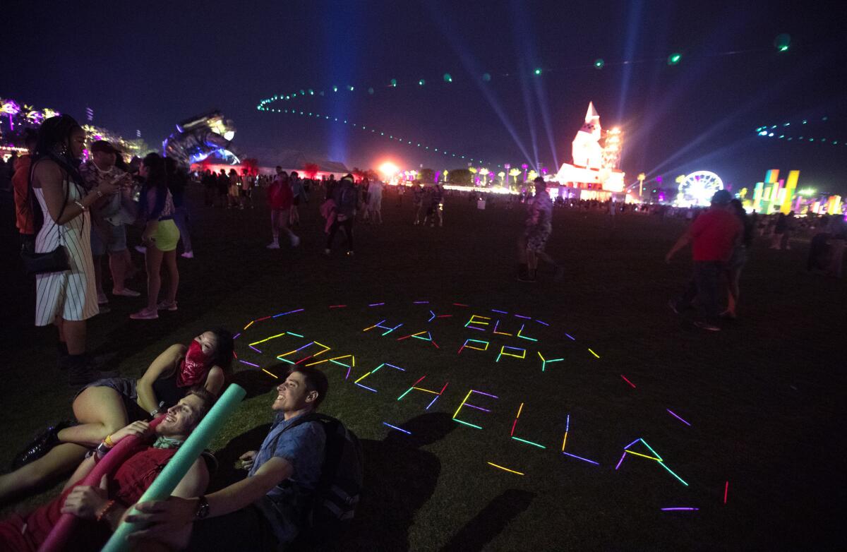 Festival goers have photos taken with glow sticks at the Coachella Valley Music and Arts Festival. (Brian van der Brug / Los Angeles Times)