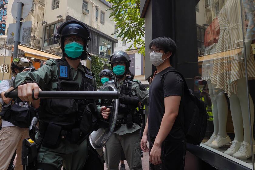 Riot police form a line as they check pedestrians gathered in the Central district of Hong Kong, Wednesday, May 27, 2020. Hong Kong police massed outside the legislature complex Wednesday, ahead of debate on a bill that would criminalize abuse of the Chinese national anthem in the semi-autonomous city. (AP Photo/Vincent Yu)