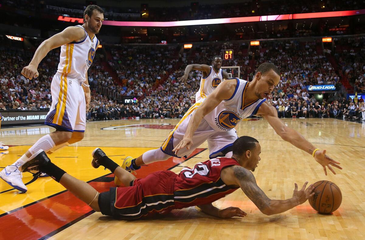 Miami guard Shabazz Napier and Golden State guard Stephen Curry chase a loose ball during the Warriors' win over the Heat, 114-97. Curry finished with 40 points and seven assists.
