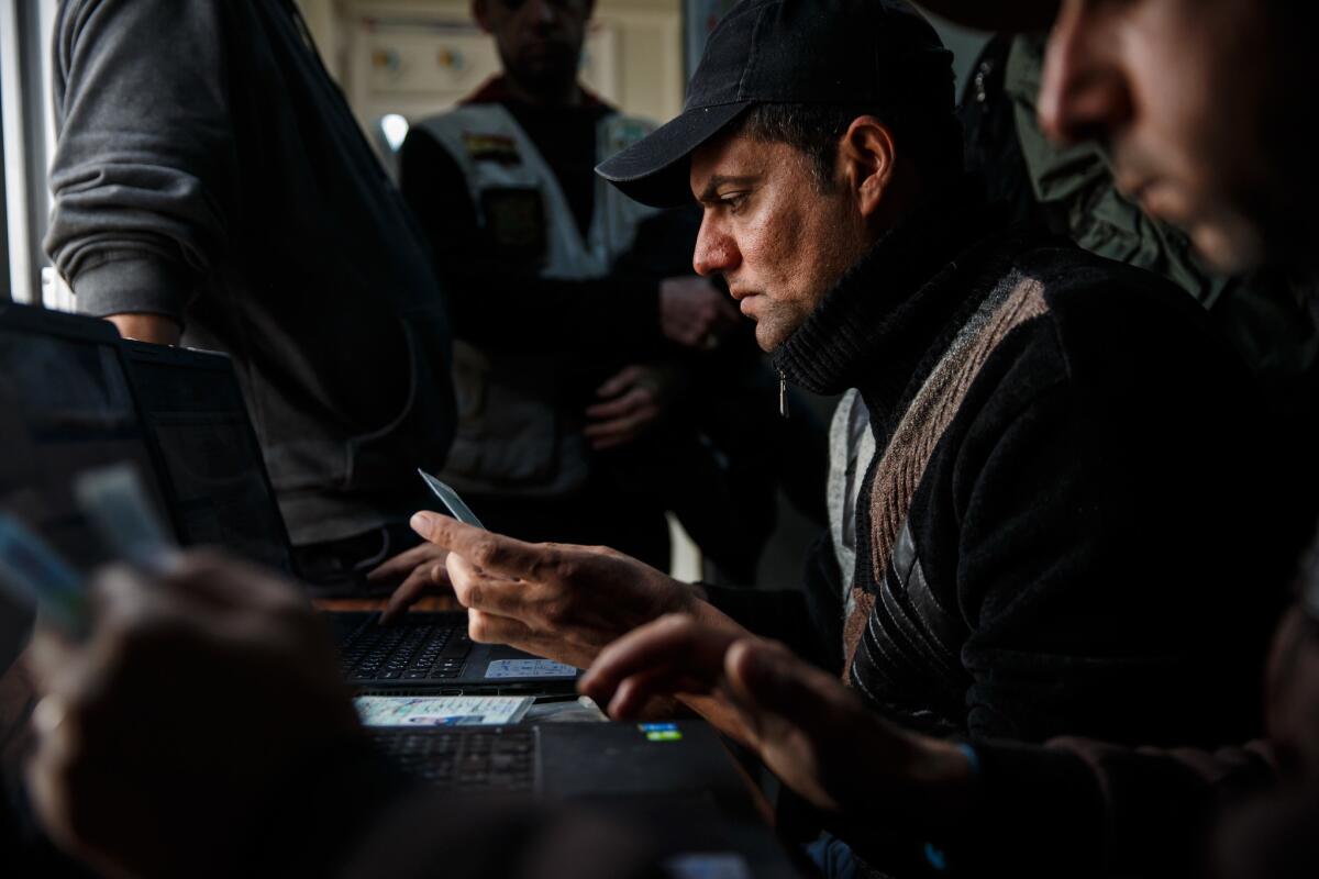 Police check identification cards against their database at the displaced persons camp in Hamam Alil.