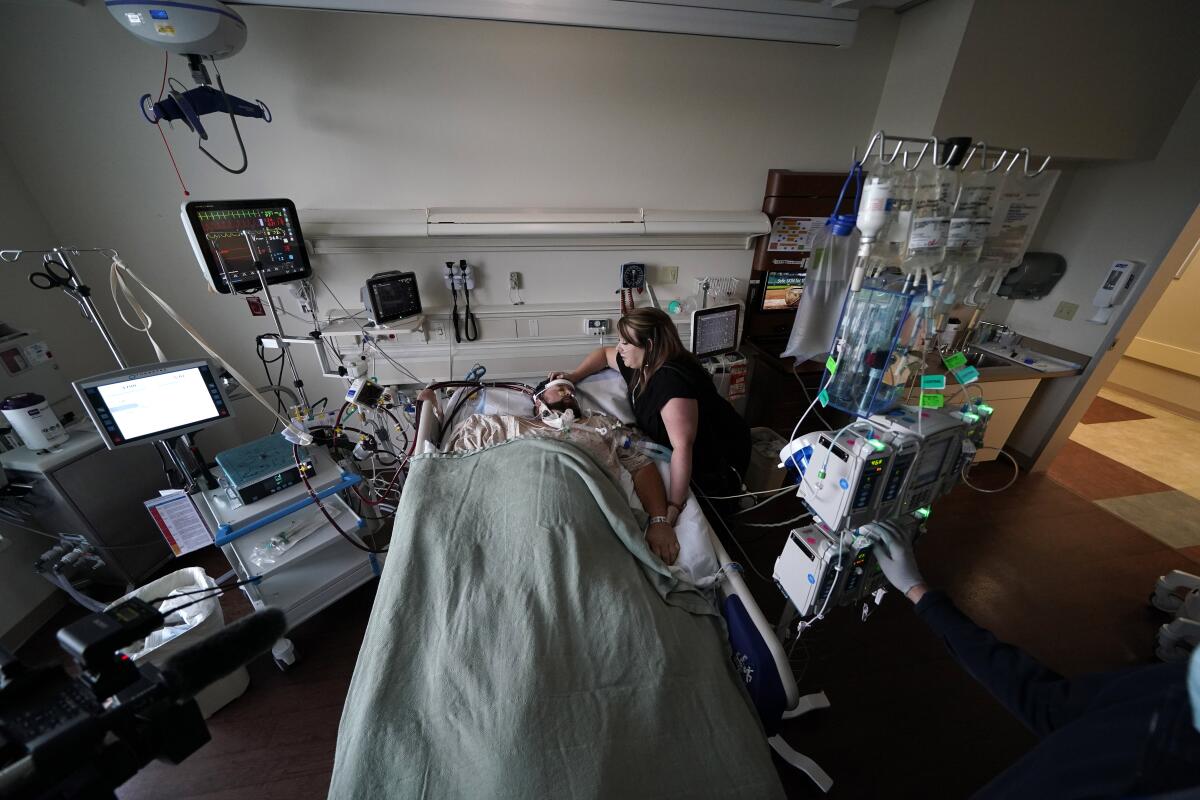 Lauren Debroeck, who is on oxygen as she recovers from COVID-19, talks to her husband, Michael, who also contracted COVID-19 and is being kept alive with the help of an oxygenation machine, at the Willis-Knighton Medical Center in Shreveport, La., Wednesday, Aug. 18, 2021. (AP Photo/Gerald Herbert)