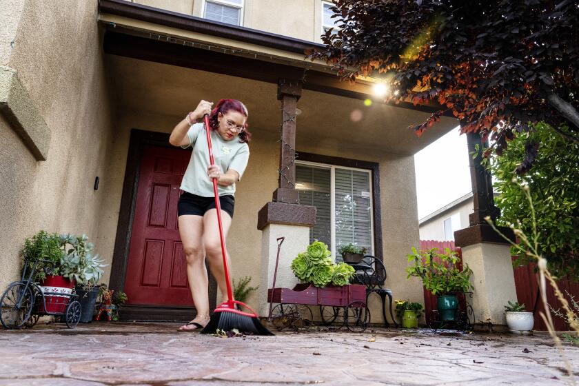 VICTORVILLE, CA - JULY 5, 2023: Gladis Avila still finds time to sweep her front porch after commuting five days a week from her home in Victorville to her job as a housekeeper at the W hotel in Hollywood on July 5, 2023 in Victorville, California. She lives in Victorville with her husband and three children.(Gina Ferazzi / Los Angeles Times)