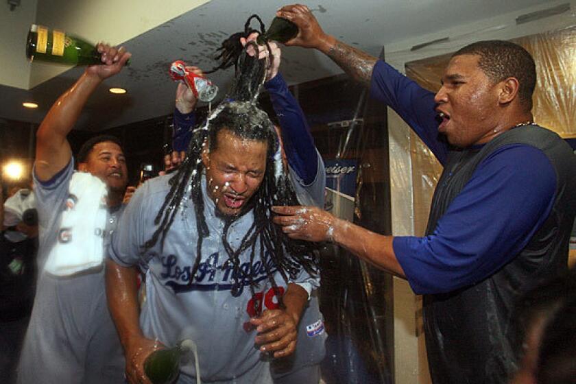 Dodgers left fielder Manny Ramirez gets doused by reliever Ronald Belisaro, right, and infielder Ronnie Belliard during the clubhouse celebration following a sweep of the St. Louis Cardinals in the National League division series on Saturday.
