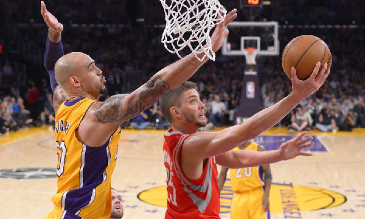 Houston Rockets forward Chandler Parsons, right, puts up a shot in front of Lakers center Robert Sacre during the first half of Tuesday's game at Staples Center.