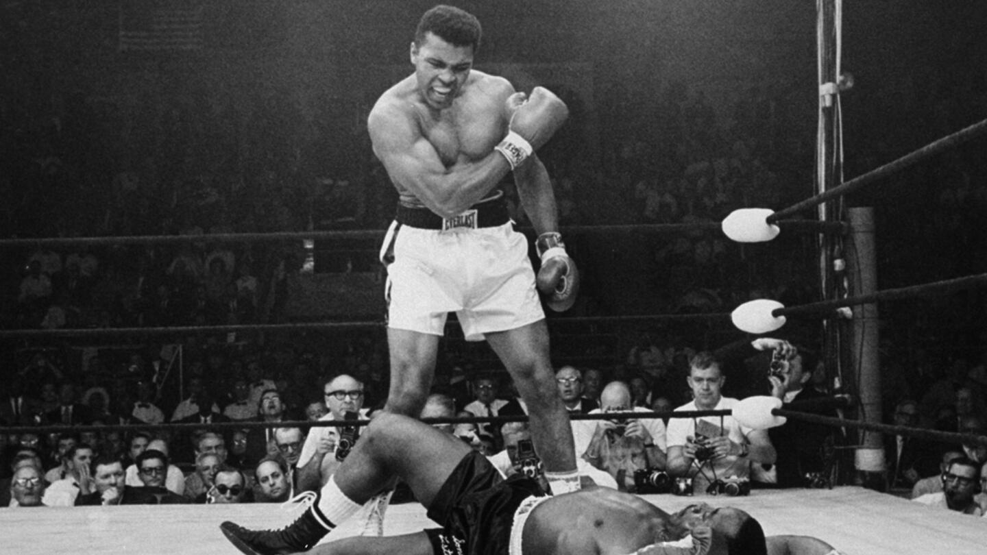 Heavyweight champion Muhammad Ali stands over fallen challenger Sonny Liston, shouting after knocking him down with a short, hard right to the jaw during their bout in Lewiston, Maine, on May 25, 1965.