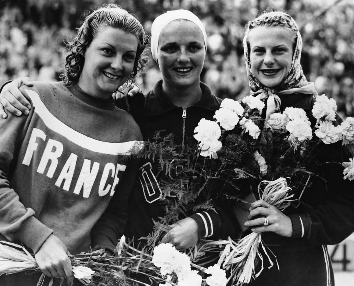 U.S. swimmer Pat McCormick, center, celebrates with France's Madeleine Moreau, left, and U.S. swimmer Zoe Jensen.